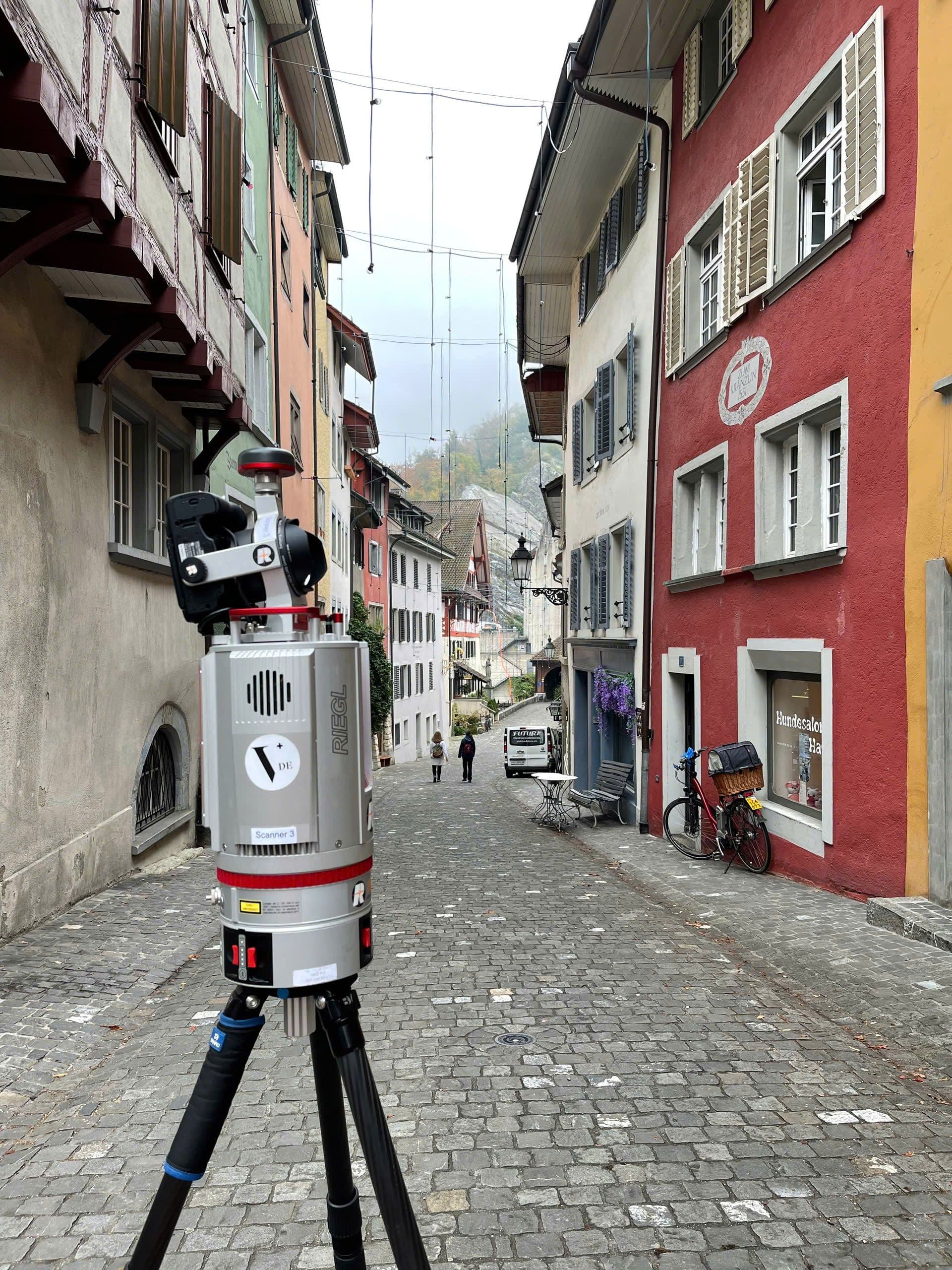 Eine malerische Altstadtstraße mit Fachwerkhäusern und einem 3D-Laserscanner im Vordergrund.