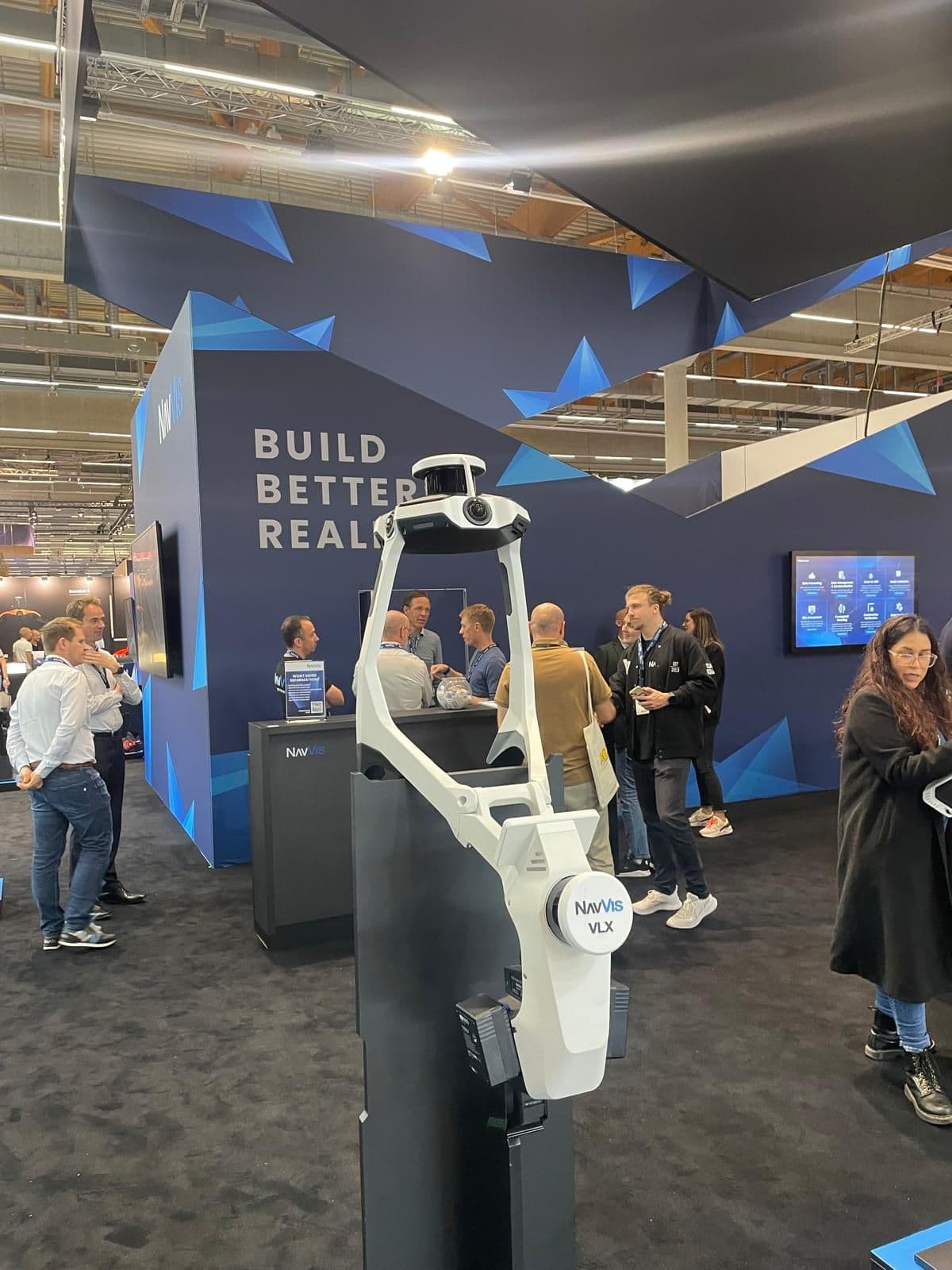 Eine Messe mit Besuchern vor einem technikorientierten Stand, an dem Produkte und Informationen präsentiert werden.