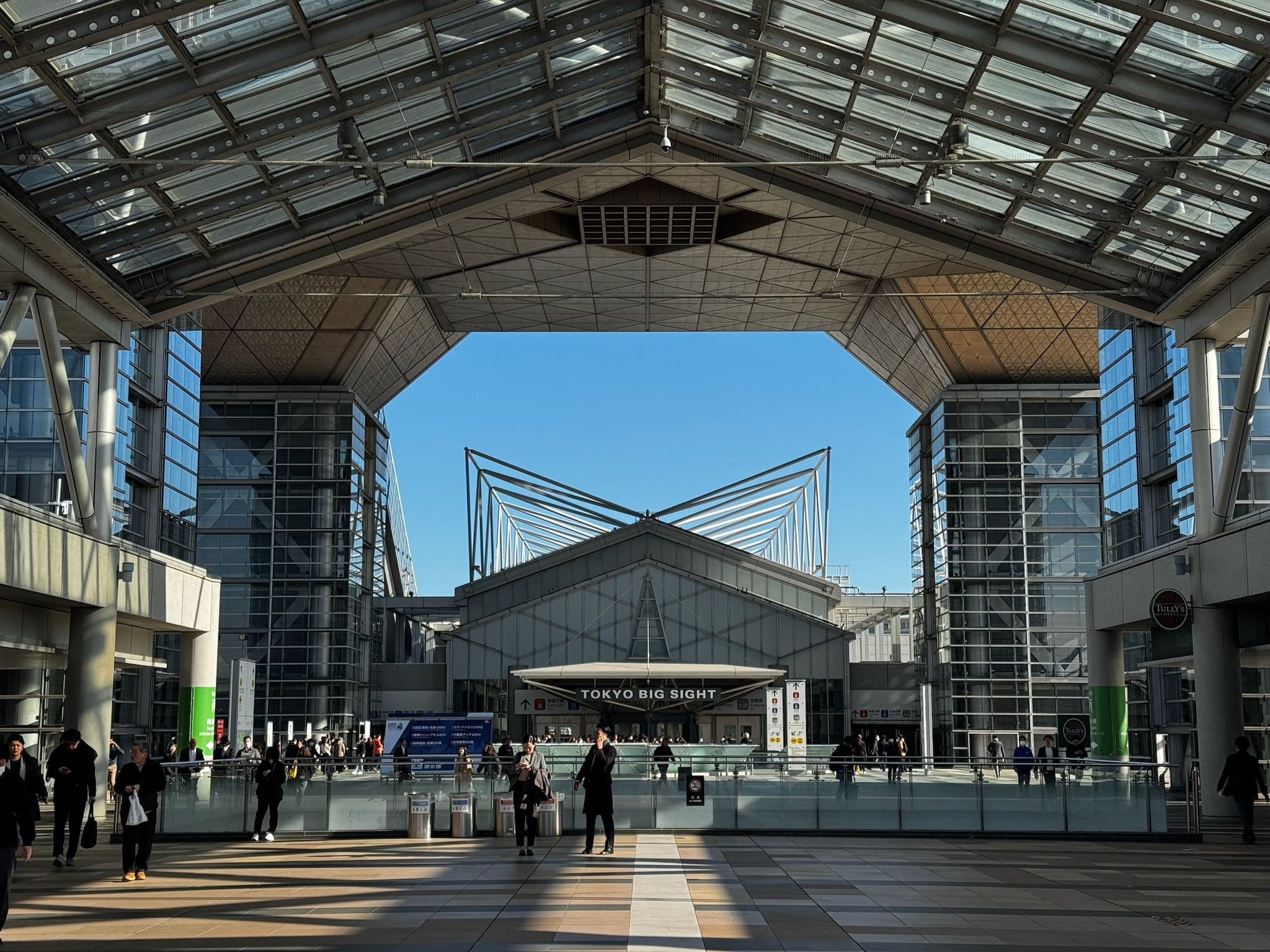 Tokyo Big Sight, modernes Kongresszentrum mit auffälliger Architektur und Glasfassaden, Menschen laufen in der Haupthalle.