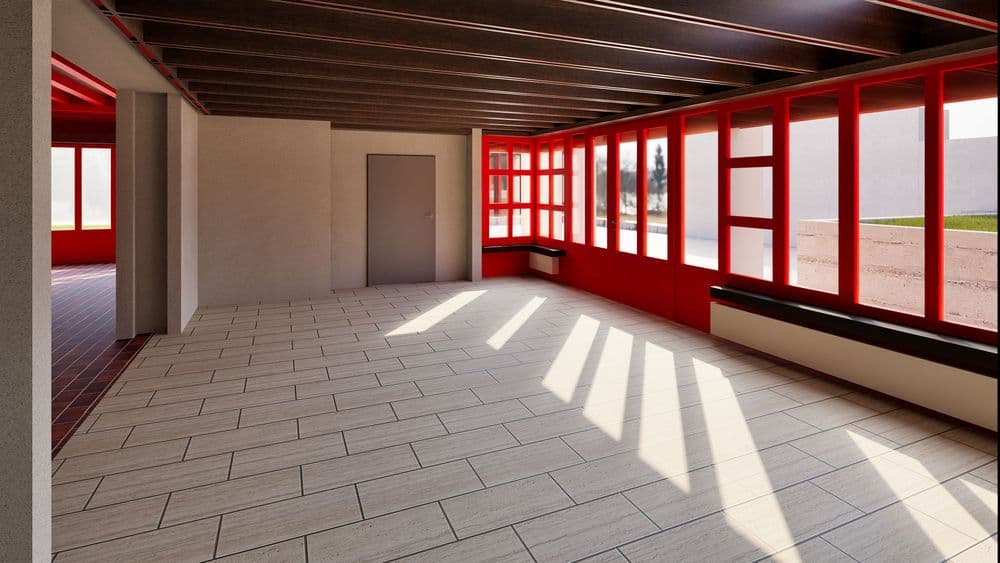 Ein heller Raum mit großen Fenstern, roten Rahmen und Holzbalkendecke. Sonnenlicht fällt auf den Fliesenboden.