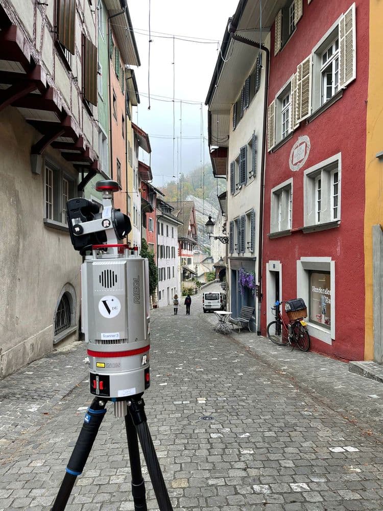 Eine malerische Altstadtstraße mit Fachwerkhäusern und einem 3D-Laserscanner im Vordergrund.