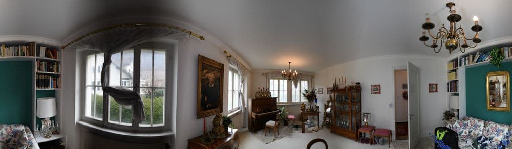 Gemütliches Wohnzimmer mit Klavier, klassischen Möbeln, Kronleuchter und großem Fenster.