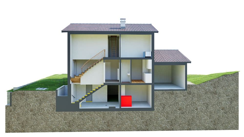 Ein modernes Einfamilienhaus im Querschnitt auf einem Hanggrundstück, zeigt mehrere Etagen mit Treppen, einem roten Kubus im Keller und grüner Umgebung.