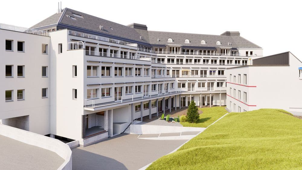 Modernes mehrstöckiges Gebäude mit großen Fenstern und Grünfläche im Vordergrund.