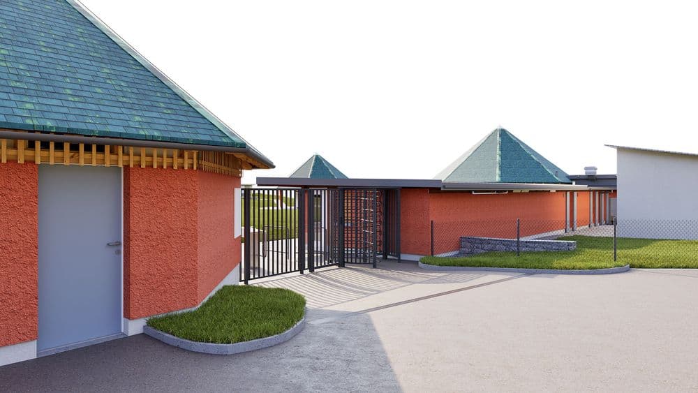 3D-Visualisierung eines modernen Gebäudekomplexes mit roten Wänden, grünen Pyramidendächern und Metallzaun am Eingang, gepflasterter Zufahrt und Grünflächen.